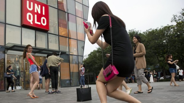 A woman poses for a photo outside the Uniqlo store in Beijing where a steamy video was filmed.