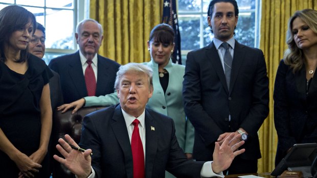 Stand up: US President Donald Trump speaks before signing another executive order cutting federal regulations while surrounded by small business leaders in the Oval Office.