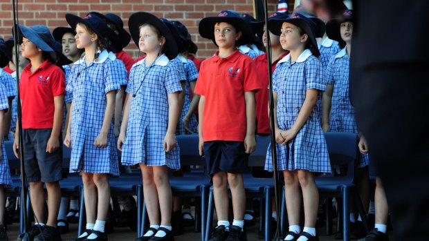 The French President, Francois Hollande, visits the French Australian School, Telopea Park. Students sing the French national anthem upon the arrival of the president. Checking out the president during the song is 8 year old Armand Bouillaud, centre. 