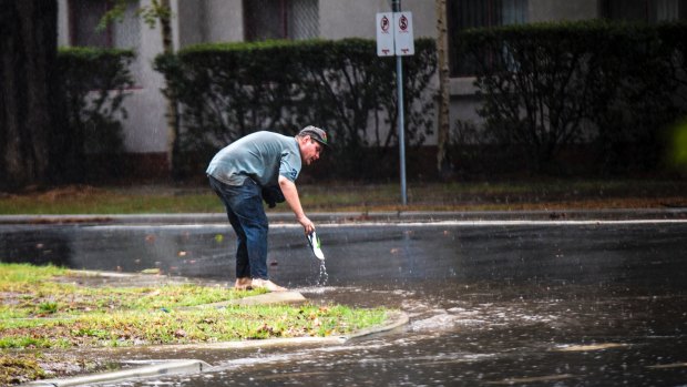 A man retrieves a thong after losing it on a waterlogged Kingston street on Tuesday.