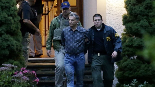 Former hedge fund manager Vitaly Korchevsky is escorted in handcuffs from his home by FBI agents