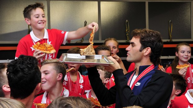 Roger Federer hands out pizza as he celebrates with the ball kids.