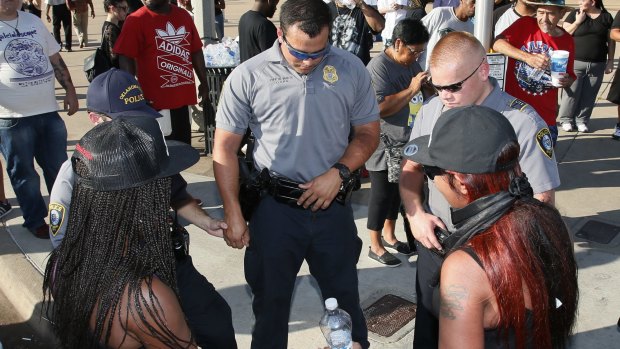 Two women join hands with Oklahoma City police officers to pray during a Black Lives Matter rally on July 10.