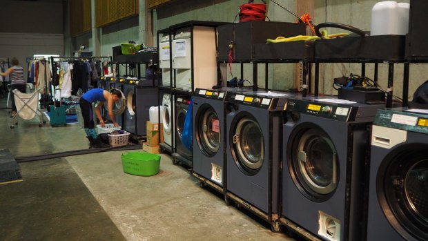 Industrial washing machines and dryers used for costumes and for personal clothing line the backstage area and travel with the tour.