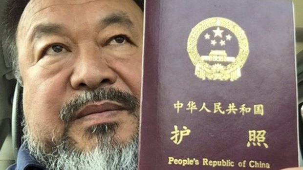 Chinese dissident artist Ai Weiwei poses with his passport in Beijing. It was returned to him on Wednesday, four years after it was confiscated by Chinese authorities.