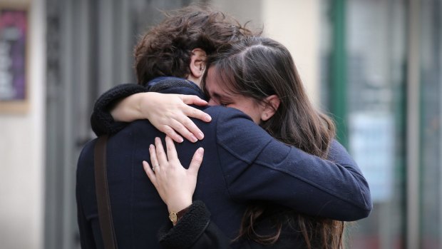 A couple embrace after laying flowers at the La Belle Equipe cafe on Saturday.