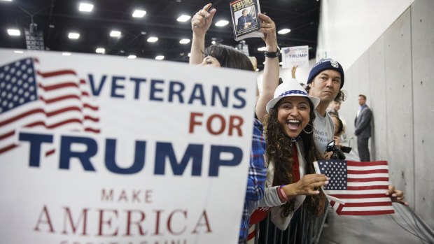 Attendees hold signs and books during the San Diego campaign event for Donald Trump.