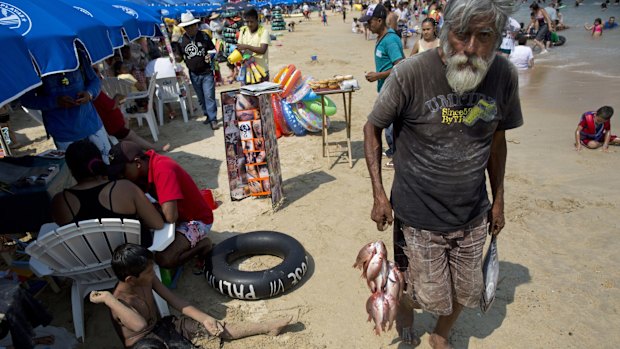 A fisherman tries to sell his fresh catch to beach goers on Caletilla beach in Acapulco, Mexico.