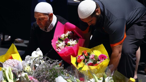 The Muslim community is not a security threat, nor should we be treated or suspected as such: two Australian Muslim men place flowers near the scene of the Lindt cafe siege.