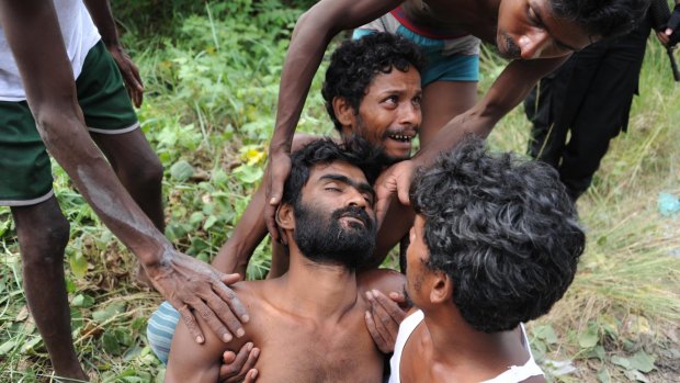 A sick migrant is assisted by other migrants on their arrival at a confinement area in the fishing town of Kuala Langsa in Aceh province, Indonesia on Friday after they were rescue.