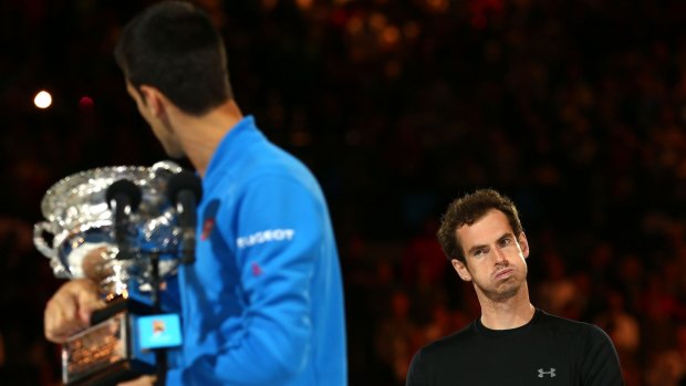 Andy Murray looks on as Novak Djokovic holds his silverware.