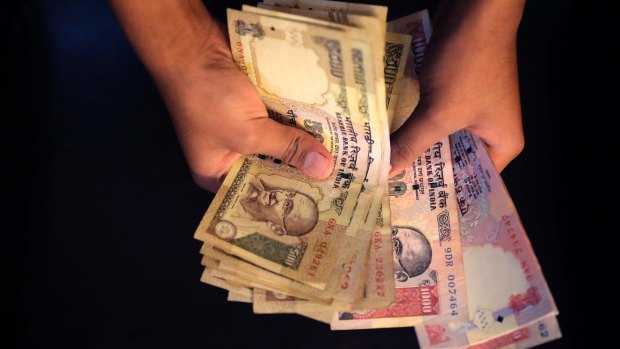 An Indian counts currency notes of 1000 and 500 denomination in New Delhi, India. The notes will be withdrawn from circulation.