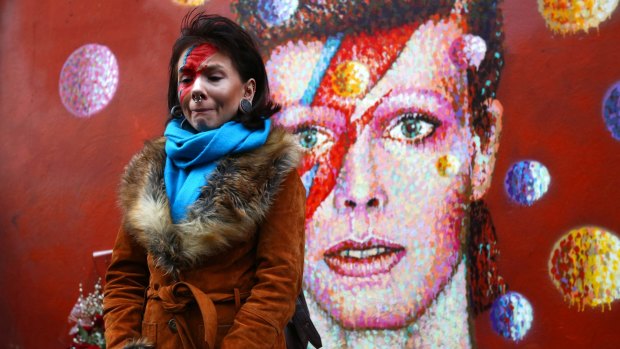 David Bowie fan Rosie Lowery placed flowers at his mural in Brixton, London, after the singer's death was announced on Monday.