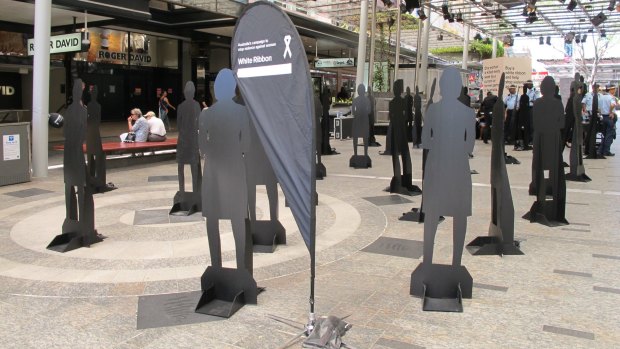 Silhouettes stand in the Queen Street Mall for White Ribbon Day.