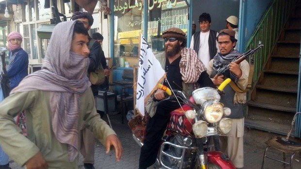 A Taliban fighter sits on his motorcycle adorned with a Taliban flag in Kunduz.