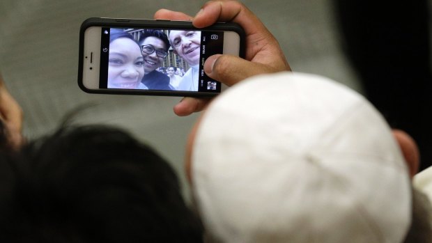 Pope Francis poses for a selfie with a couple attending his weekly general audience last month