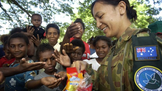 Corporal Aspen Williams hands out Christmas presents to local children presents for Christmas in a small village on the out skirts of Honiara.
