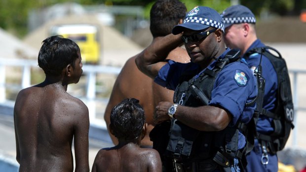 Young local aboriginal kids play on the main wharf on Palm Island while Police officers from the Personal Safety Response Team PSRT patrol the island in December 2004
