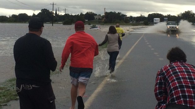 People rush to try and save the occupants of a car swept away in Maitland. 