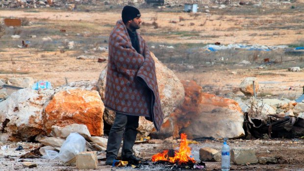 A man of eastern Aleppo standing next to a fire in western rural Aleppo, Syria.