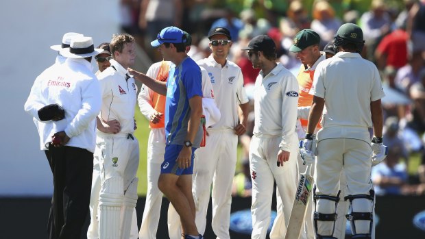 Steve Smith is assessed after being hit by a bouncer.