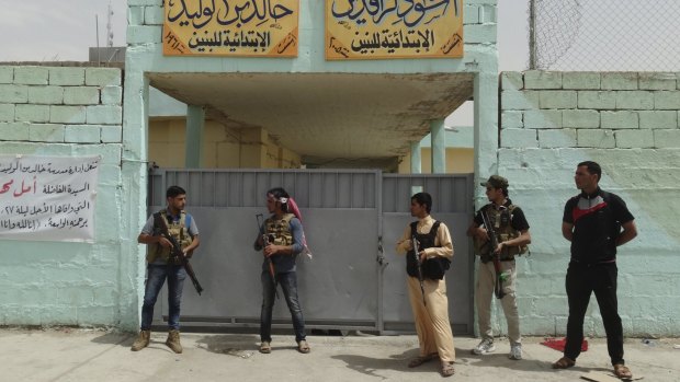 Sunni fighters stand guard near a school used as a shelter for displaced people in Ramadi, before IS took the village.