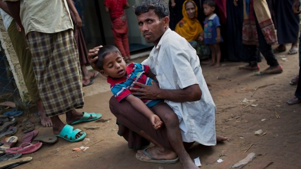 A Rohingya Muslim man holds a child with fever