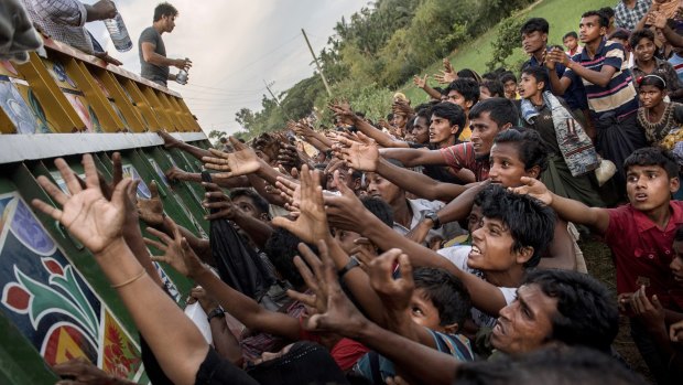 Rohingya reach out to collect food and water rations at a refugee camp in Bangladesh.
