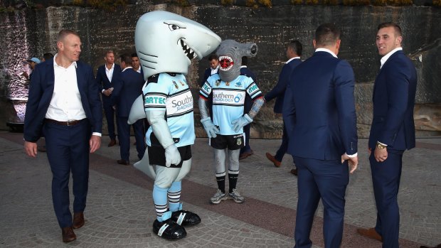 Cheer squad: Luke Lewis walks past the Sharks mascots, MC Hammerhead and Mr Sharkey, during the NRL grand final fan day at Sydney Opera House on Thursday.