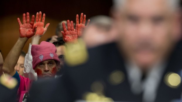 A demonstrator from Code Pink raises his hands as General John Campbell, commander of US forces in Afghanistan, right, speaks during a Senate committee hearing in Washington earlier this month.