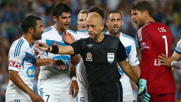 Melbourne Victory's players argue with referee Strebre Dilovski as he makes the decision to award a penalty to Sydney FC.