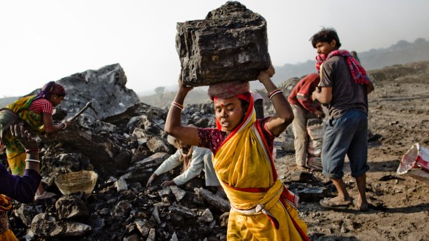 Local villagers work to scavenge coal illegally from an open-cast coal mine in the village of Jina Gora near Jharia, India. 