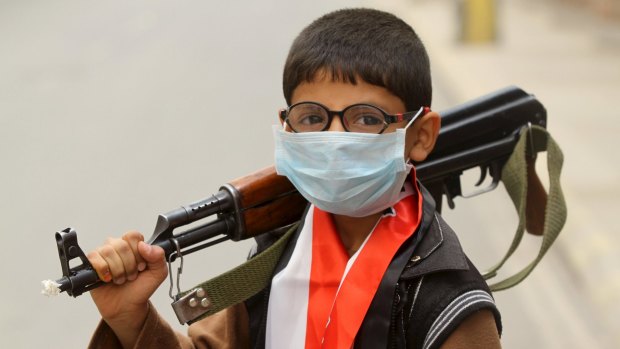 A boy holds a machine gun in Sanaa, Yemen, ahead of a sandstorm.