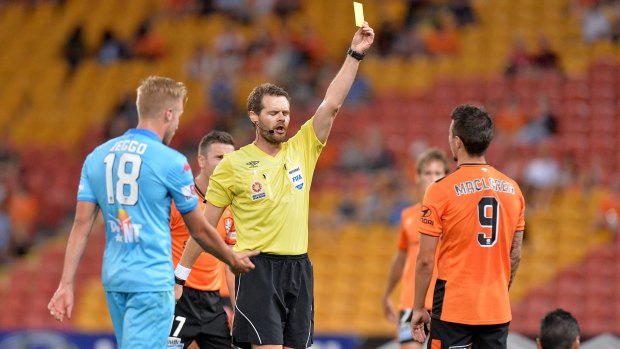 Jamie Maclaren of the Roar is given a yellow card by Referee Chris Beath.