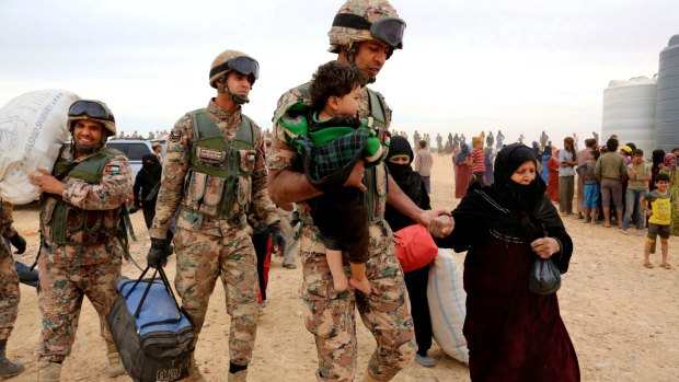 Jordanian soldiers help women and children enter into Jordan on Wednesday.
