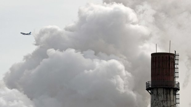 An airliner flies past a coal-fired power plant in Beijing last month.