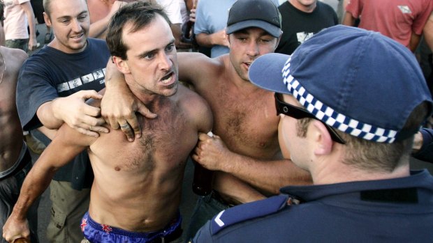 A man confronts police, holding a beer bottle during the Cronulla riots.