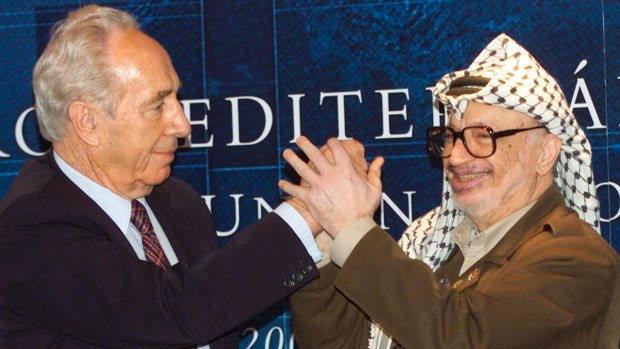 Palestinian leader Yasser Arafat, right, clasps hands with then Israeli Foreign Minister Shimon Peres.