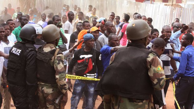 Mali troops try to control a crowd of onlookers near the Radisson Blu hotel after the attack.