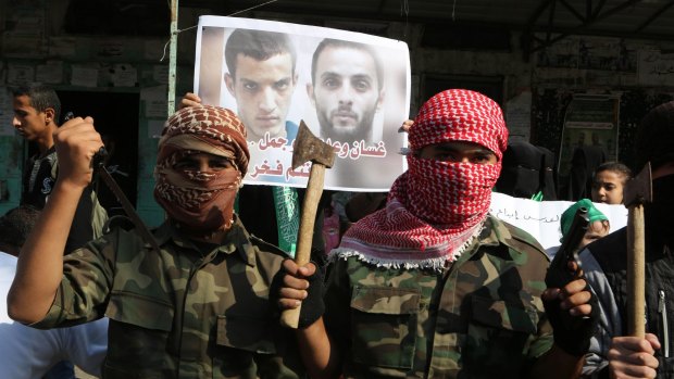 Masked Palestinians hold knives and axes as they celebrate an attack on a Jerusalem synagogue.