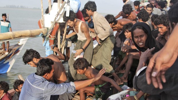 An Acehnese fisherman, lower left, help migrants to transfer to his boat on the sea off East Aceh, Indonesia on Wednesday, May 20, 2015. 