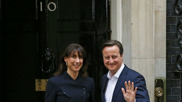 Britain's Prime Minister David Cameron waves as he arrives with his wife Samantha at 10 Downing Street, London, on Friday.
