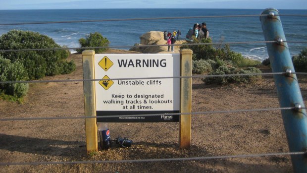 Tourists at Victoria's Twelve Apostles ignore a fence and sign to gain a better view.