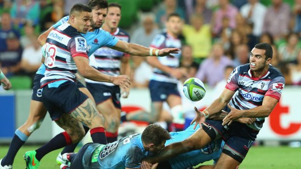 Jack Debreczeni of the Rebels passes as he is tackled by Bernard Foley of the Waratahs.