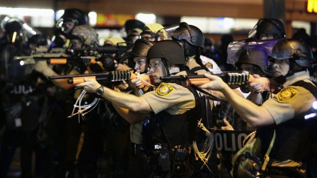 Police officers point their weapons at demonstrators in Ferguson in August.