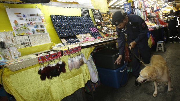 A Thai policeman patrols with a bomb-sniffing dog at a night market in Bangkok on Thursday.