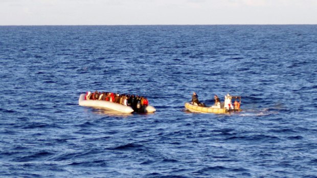 An Italian Navy rescue crew on a dinghy, right, approaches migrants on a boat some 65 kilometers from the Libyan capital, Tripoli. Spanish authorities have called off the search for 20 migrants who fell into the Mediterranean on Friday south of Almeria.