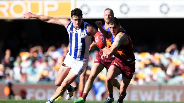 Tom Rockliff of the Lions (right) and Scott Thompson of the Kangaroos chase the ball during the Round 23 AFL game between the Brisbane Lions and the North Melbourne Kangaroos at the Gabba on  Saturday, August 26, 2017.