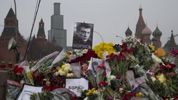 Signs reading "propaganda kills" and "Fight" lie among flowers and photos of slain opposition figure Boris Nemtsov at the site of his death.
