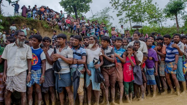 Rohingya Muslim men, who crossed over from Myanmar into Bangladesh, wait for their turn to collect food.